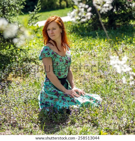 Redhead girl sitting in the flower field