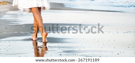 Woman walking on sand beach leaving footprint in the sand