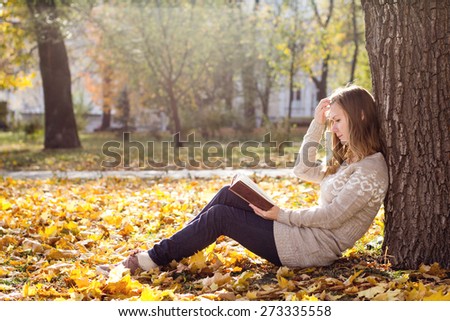 Young beautiful woman reading a book at the park