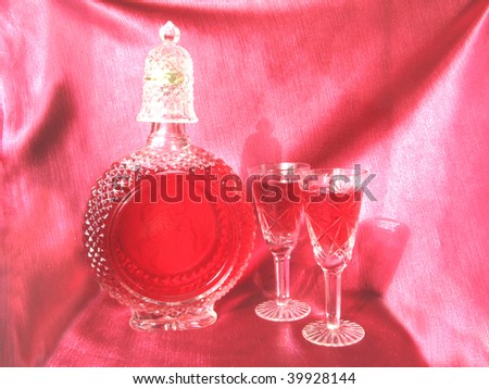 crystal carafe of red wine and two goblets on red background