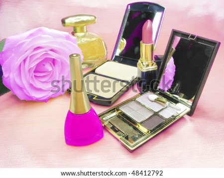 violet lipstick powder pink rose eye-shadows and perfume on satin cloth background