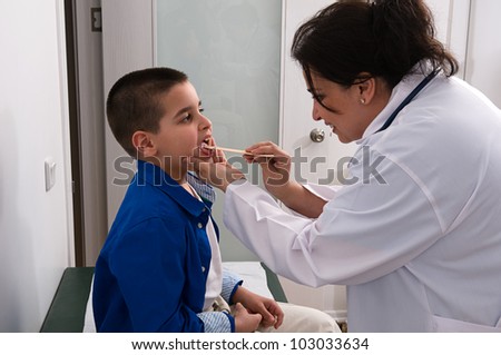 Pediatrician examining little childÃ¢Â?Â?s  throat with tongue depressor