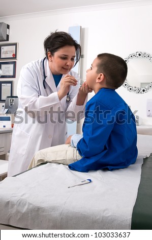 Doctor checking throat of a little boy with tongue depressor.