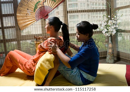 Asian woman Thai massaging beautiful adult woman at spa salon