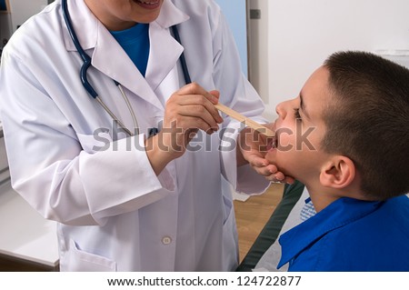 Doctor checking throat of a little boy with tongue depressor