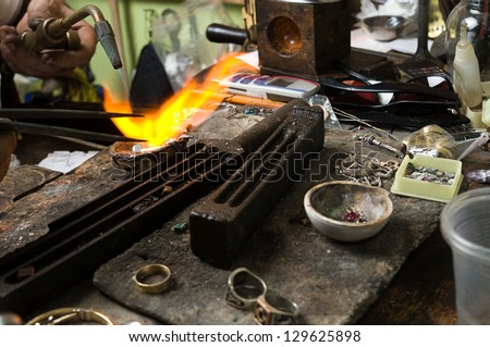 Jeweler melting silver in crucible with gasoline burner for making jewelry
