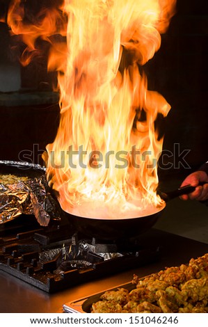 Professional cook preparing food on flame