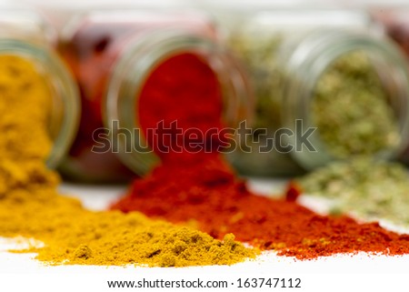 Spices being poured out of spice jars isolated on white background