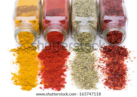 Different spices spilling from spice jars isolated on white background