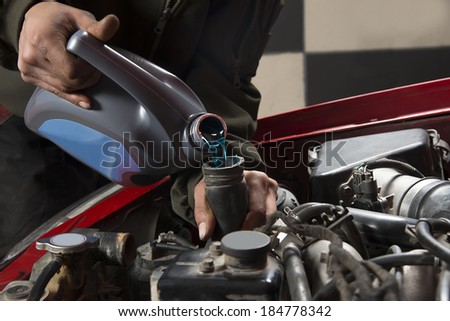 Car repairman pouring antifreeze into old engine