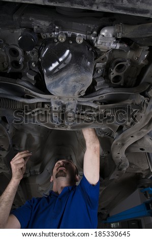 Auto repairman working under an old car