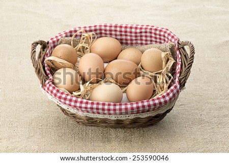 Basket full of eggs over jute background.