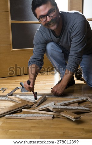 Vertical image of a worker disassembling wooden floor ruined from moisture and water leak