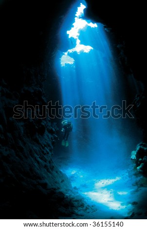 Silhouette of a diver with sun rays in a cave