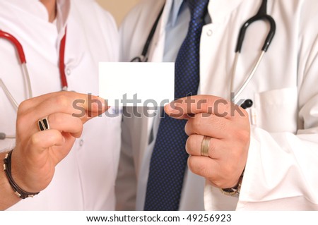 Two medical doctors with stethoscope holding a business card.