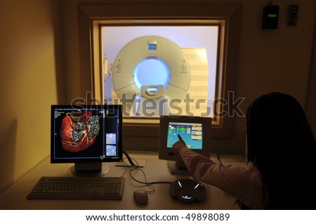 Magnetic Resonance Imaging machine from control room and a nurse showing results -a series of MRI.