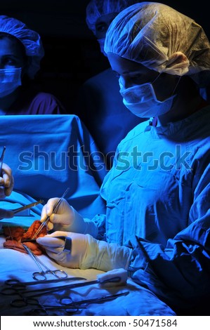Medical team performing a operation in a dramatically lightened surgery room - a series of SURGERY related images.