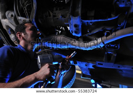 Auto mechanic working under dramatically lightened car - a series of MECHANIC related images.