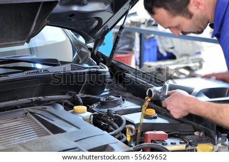 Car mechanic changing oil - model and oil motion blurred.