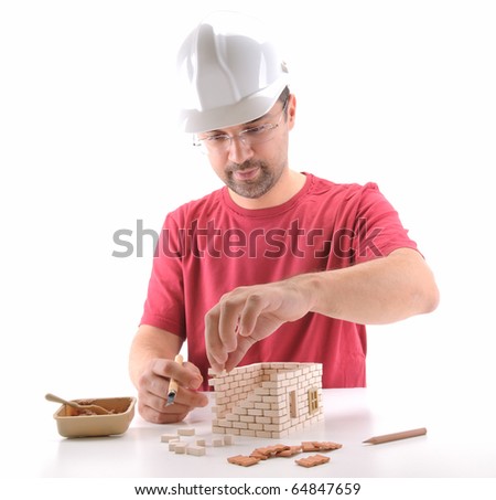 Adult man building a brick house isolated on white - a series of BUILDING A HOUSE images.