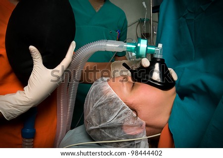 Applying anesthesia to adult female during surgery