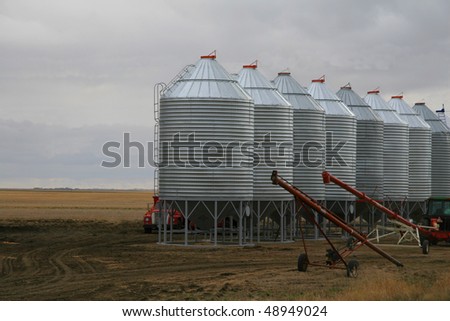row of steel grain bins with two grain augers