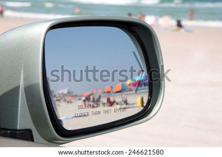 Beach scene through a rear view mirror.  Focus is on the words 