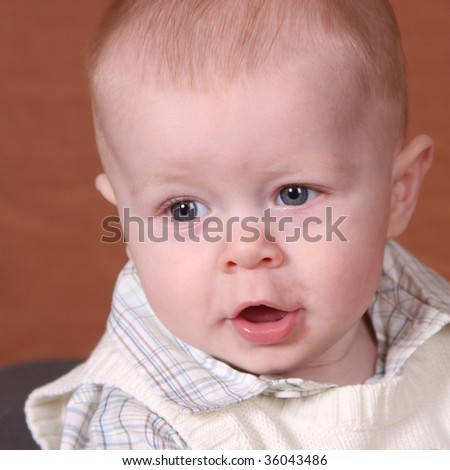 Baby boy in a cardigan sweater looks like he is talking
