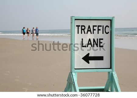 Older adults walking on Daytona Beach near a traffic sign.