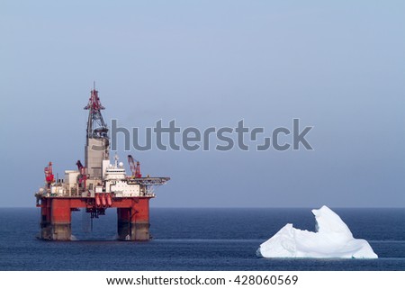 Iceberg next to a offshore oil drilling platform.