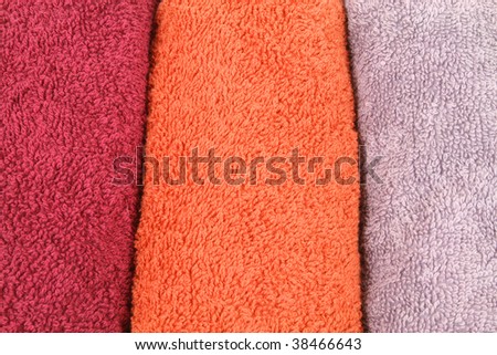 Background of three colorful towel rolls - orange, maroon and violet
