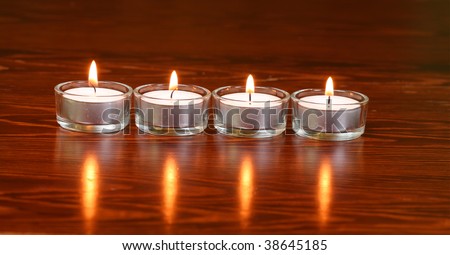 Burning candles on the dark wooden surface