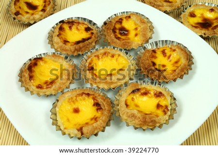 Traditional portuguese egg tarts - pastries pasteis de nata in tin moulds on white plate