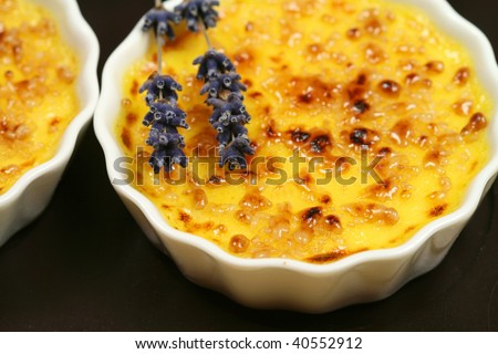 Creme brulee with lavender flower on black background. Traditional french dessert in flavored version