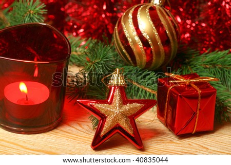 Christmas ornaments in red color - star, gift box, candle and glass ball with green alive Christmas tree branch