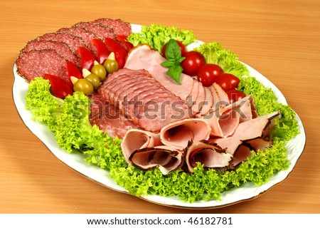 Cutting sausage, ham and cured meat on a celebratory plate with garnish