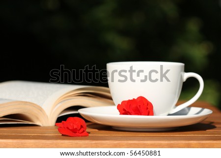Relax in the garden - coffee, book and red begonia flowers