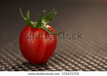 Single wet cherry tomato with fresh water drops