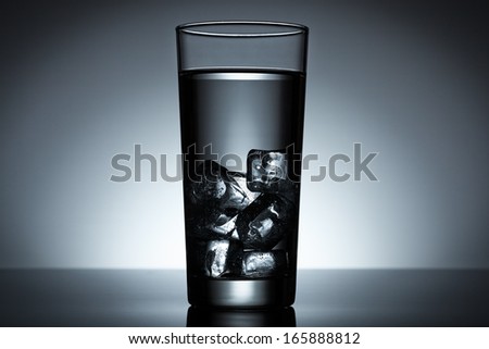 Glass of water filled with ice cubes backlighted