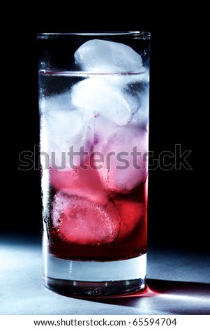 Red syrup / juice in glass of water with ice cubes, backlit