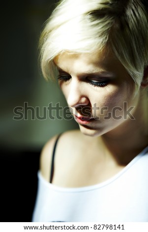 Young blonde sad woman looks at the ground
