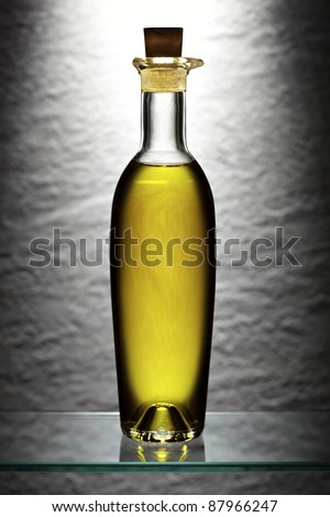 Yellow backlit olive oil bottle in front of stone wall