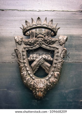 Old coat of arms with the head of a lion below realistic crossed paws in the central shield surmounted by a crown