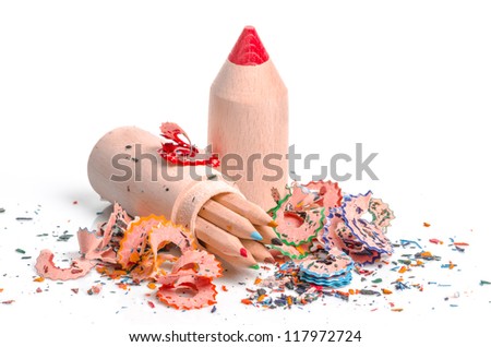 Artistic still life witha pencil-shaped case filled with coloured pencil crayons surrounded by wood shavings from sharpening them on a white studio background
