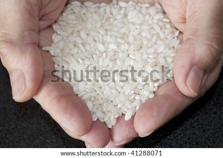 Handful of rice. Adult\'s hands offering white rice.
