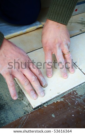 Detail of mason tiler hands laying a tile on the floor