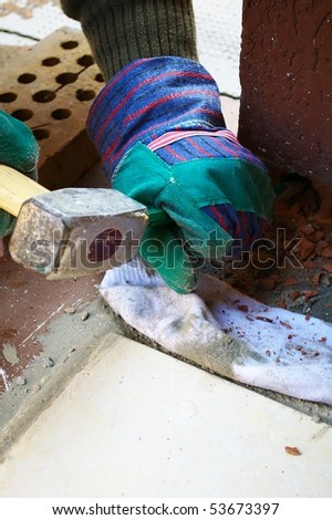 Closeup of worker hand beating a wall with hammer and chisel