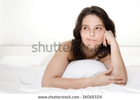 Beautiful woman lying on bed hesitating isolated on white
