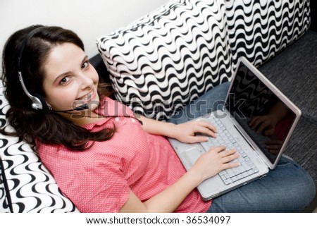 Smiley woman with headphones and laptop sitting on couch