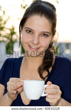 Pretty woman holding mug sitting in garden